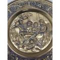 A vintage wall hanging brass plate with a family scene