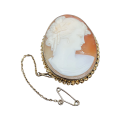 A beautifully carved cameo mounted in a rich gold setting with a safety chain.