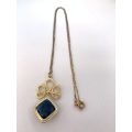 Pendant and Chain - Gold Colour Square Pendant Hung at angle from decorative pattern on Gold Colo...