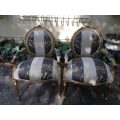 A Pair of French Style Arm Chairs Hand Gilded With Gold Leaf And Upholstered In an Imported Scrip...