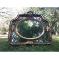 A French Ornate carved mirror with a bevelled oval centre section