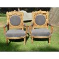 A 20th Century French Style Ornately Carved and Gilded Pair of Arm Chairs