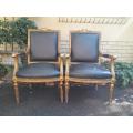 A Pair of French Style Carved and Gilded Armchairs Upholstered in Leather