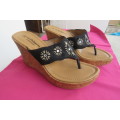 Pair of wedge heel sandals.Slip on style. Black band with embroidery and stones. Cork heels, Size 6