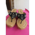Pair of wedge heel sandals.Slip on style. Black band with embroidery and stones. Cork heels, Size 6