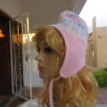 Cosy pink knitted earflap hat with ties. In blue, white pattern. Fleece inner. With pompom.