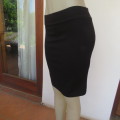 Black bodycon stretch polyester knee length skirt in size 32/8 by `MASSUMI`. New condition.