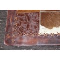 A BEAUTIFUL RECTANGULAR COWHIDE RUG/ MAT WITH HAND STITCHED DETAILING AND BROWN TONES
