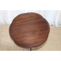 A MAGNIFICENT TEAK OCCASIONAL TABLE WITH BROAD RIMMED DETAILED TOP AND THREE BRASS TOE CAPS