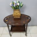 An exquisite Teak "Butlers" trolley on castors with brass hinges; Opens into a removable oval table