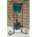 A gorgeous wrought iron plant stand with a large stunning emerald green glass bowl