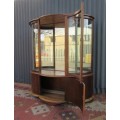 A stunning and beautifully made curved glass Teak show cabinet with solid brass embellishments