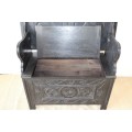 A superb antique hand-carved blackened oak monks bench with a storage chest in the base