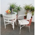 A gorgeous white painted wicker "all weather" outdoor/ patio table with a glass top and a chair
