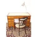 A beautiful vintage knee-hole writing desk w/ an off-white leather top & 9x drawers w/ brass handles