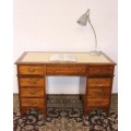 A beautiful vintage knee-hole writing desk w/ an off-white leather top & 9x drawers w/ brass handles