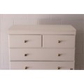 A tall 4-over-2 white painted chest of drawers with brass handles and ample storage space