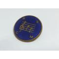 A VINTAGE ENAMEL AND BRASS MUSIC RELATED BADGE