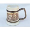 A heavy vintage pottery jug with metal bands and metal handle featuring a winemaker theme