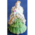 VINTAGE LACE AND PORCELAIN FIGURINE SITTING ON A CHAIR.