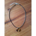 Black faux leather waxed cord necklace with round tortoise shell resin pendant The necklace has an e