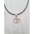 Black faux leather waxed cord necklace with 2 entwined hearts pendant The necklace has an extender c