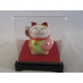 A CUTE CHINESE PORCELAIN MANEKI-NEKO (LUCKY CAT) IN PERSPEX BOX