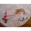 A small round vintage hand embroidered cloth with hand crocheted border