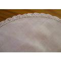 A small round vintage hand embroidered cloth with hand crocheted border