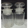 A SET OF 2 STORAGE GLASS BOTTLE CONTAINERS THE ONE LID WAS REPAIRED BEFORE SOLD AS IS