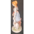 A FARM GIRL WITH HER DOG CARRYING FLOWER PORCELAIN FIGURINE SOLD AS IS