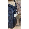 A BLACK GUESS SLING HAND BAG HAS SOME ARE AND TARE ON IT