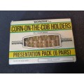 A vintage gold plated corn on the cob holders in its original packaging