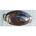 AN OVAL STAINLESS STEEL SERVING PLATTER WITH GOLD TONE HANDLES SOLD AS IS