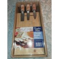 A NEVER BEEN USED GORDON BLU CHEESE BOARD AND THREE KNIVES SOLD AS IS