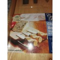 A NEVER BEEN USED GORDON BLU CHEESE BOARD AND THREE KNIVES SOLD AS IS