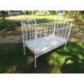 Antique white painted wrought iron baby cot with drop sides.