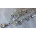 A SPARKLING SINGLE STRAND CRYSTAL NECKLACE WITH 6 SIDE DROP CRYSTALS AND A CENTRAL DROP PENDANT