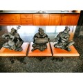 Set of three Balinese patinated bronze figures of seated musician, on wooden bases