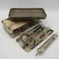 Vintage glass syringe set in metal tin