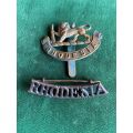 SOUTHERN RHODESIA BRASS CAP BADGE AND SHOULDER TITLE-WORN FROM 1940-1956 BY VARIOUS UNITS WHICH DID