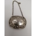 A VINTAGE SILVER PLATED DECANTER LABEL MARKED BRANDY