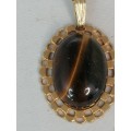 A PRETTY TIGERS EYE PENDANT ON A GOLD CHAIN MARKED NS