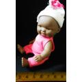 Small African Baby doll in a pink suit. looks like a Berenguer doll