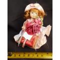 collectable small porcelain doll, Heidel, bearing flowers and a gift