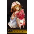 collectable small porcelain doll, Heidel, bearing flowers and a gift