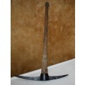 This is a vintage farming pickaxe. It  features a wooden handle and metal spear