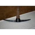 This is a vintage farming pickaxe. It  features a wooden handle and metal spear