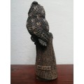 Beautiful, heavy sculptured owl on a tree trunk.