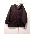 Black Woolworths rain jacket 5-6 with reflector strips and large zipped pocket at back